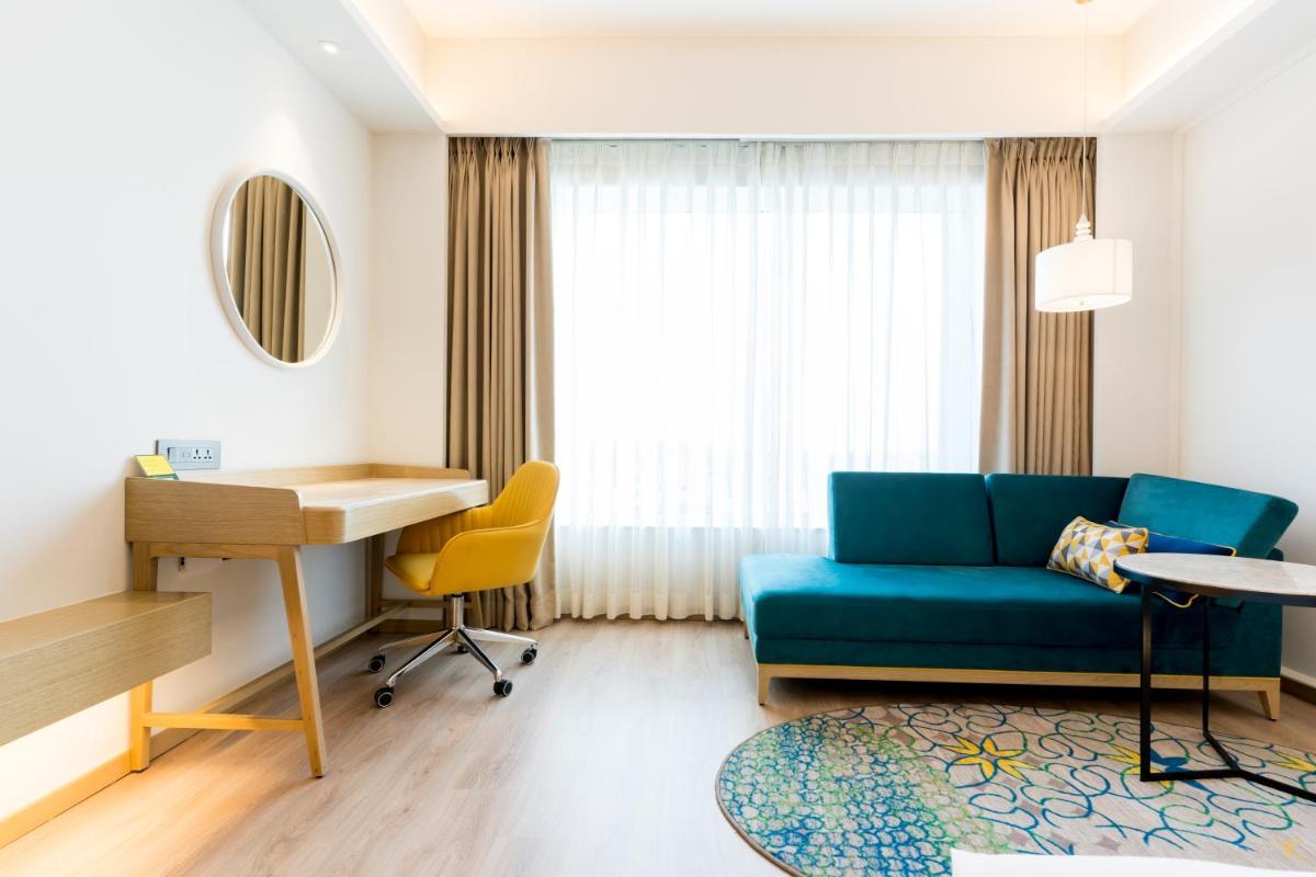 a living room with a blue couch and a desk at Holiday Inn Lucknow Airport by IHG in Lucknow