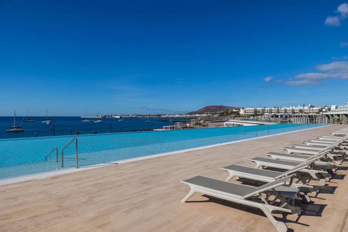 Una fila de tumbonas junto a una piscina. en Barceló Playa Blanca Royal Level - Adults Only, en Playa Blanca