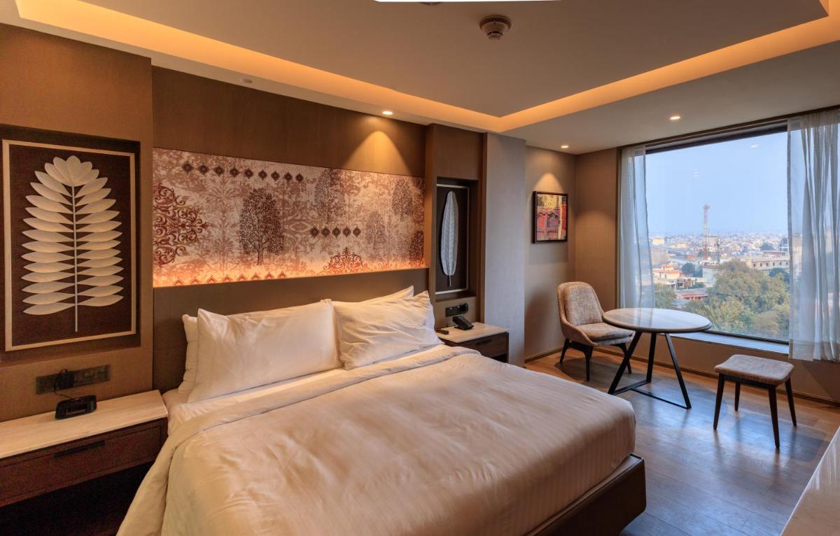 a hotel room with a bed and a table and a window at Courtyard by Marriott Amritsar in Amritsar