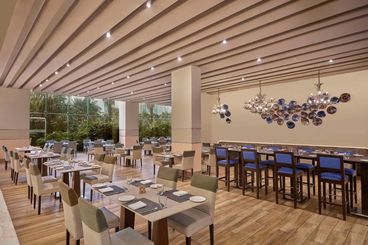 a restaurant with tables and chairs in a room at DoubleTree by Hilton Gurugram Baani Square in Gurgaon
