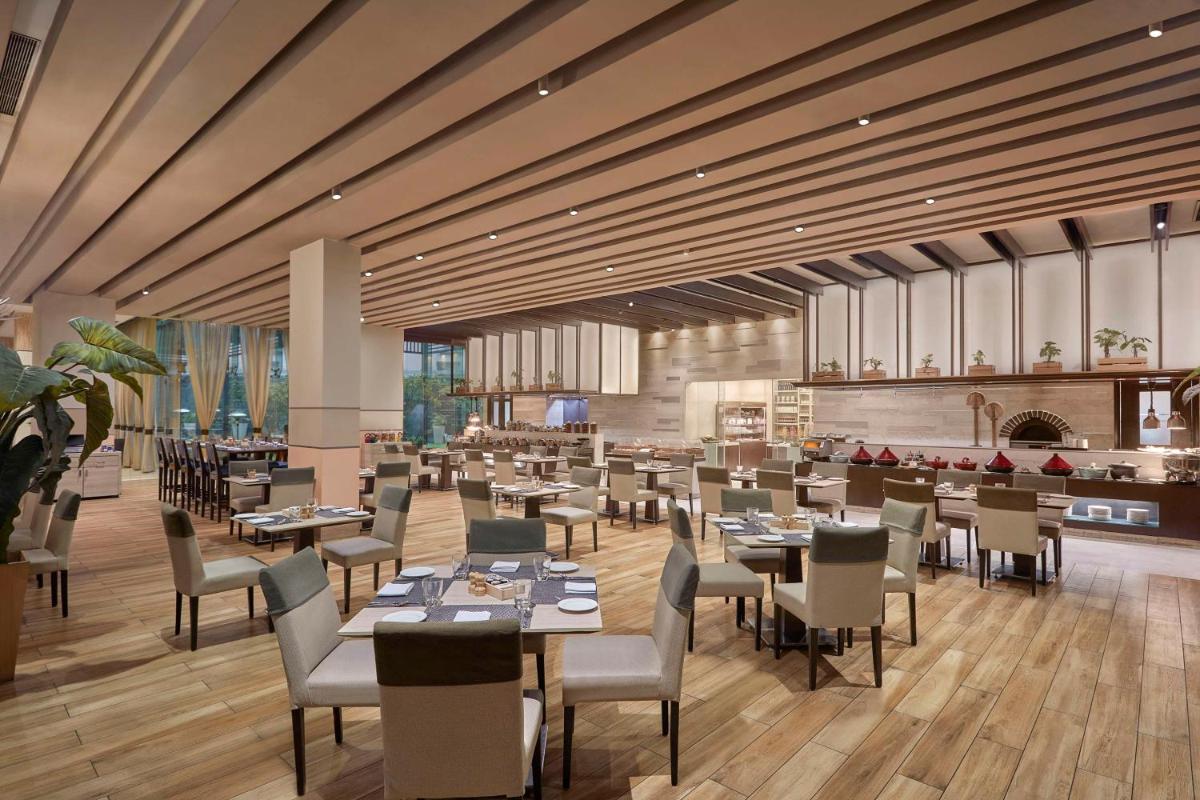 a restaurant with tables and chairs and a fireplace at DoubleTree by Hilton Gurugram Baani Square in Gurgaon
