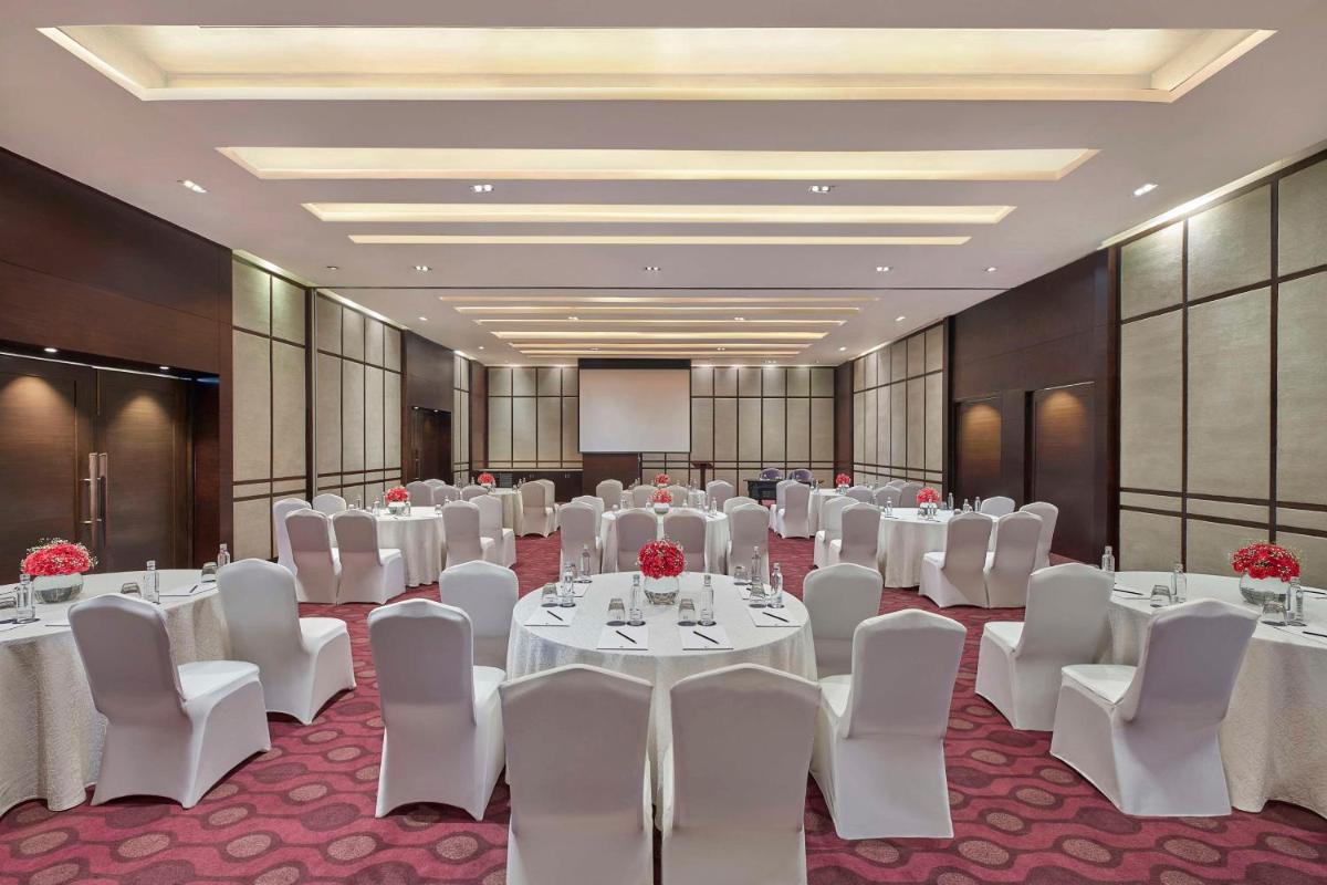 a conference room with white tables and white chairs at DoubleTree by Hilton Gurugram Baani Square in Gurgaon