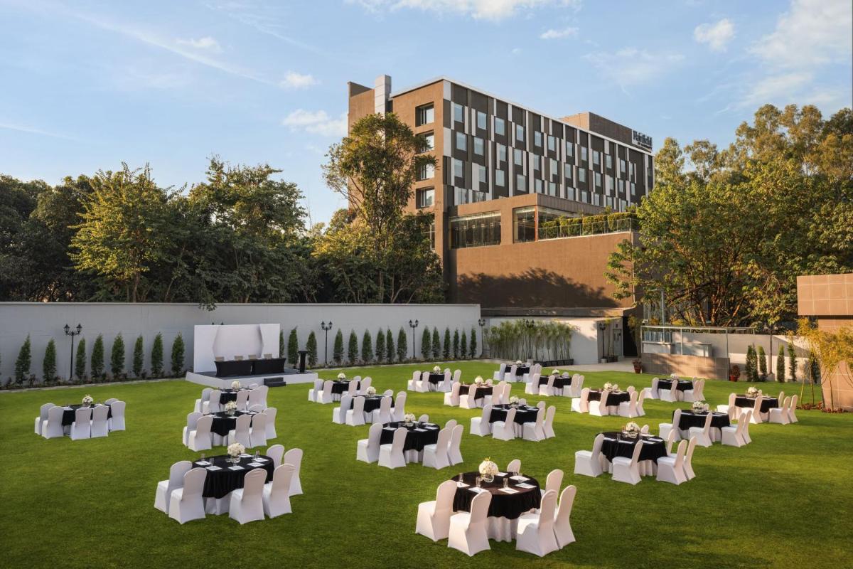 a lawn with tables and chairs in front of a building at Fairfield by Marriott Dehradun in Dehradun