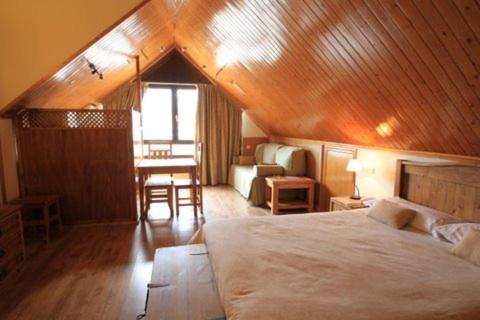 Un dormitorio con una cama grande y un techo de madera. en Aparthotel Sarrato, en Sallent de Gállego