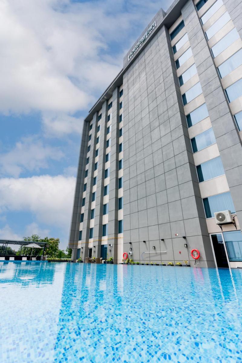 a building with a swimming pool in front of it at Holiday Inn Lucknow Airport by IHG in Lucknow
