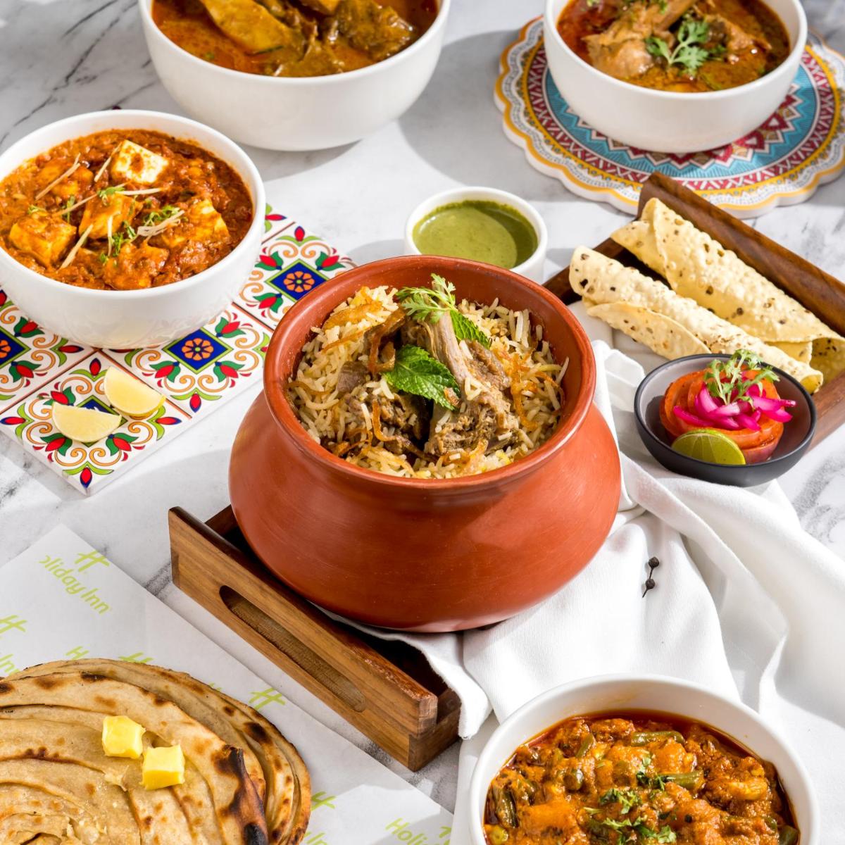 a table with several bowls of food on it at Holiday Inn Lucknow Airport by IHG in Lucknow