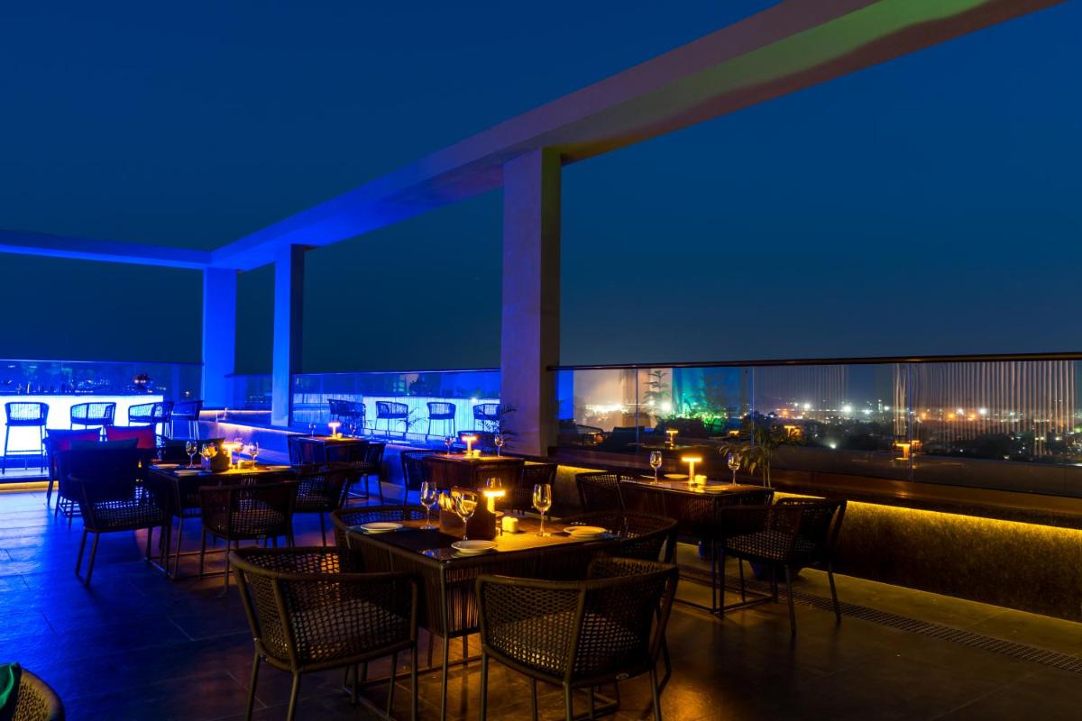 a restaurant with tables and chairs at night at Holiday Inn Lucknow Airport by IHG in Lucknow