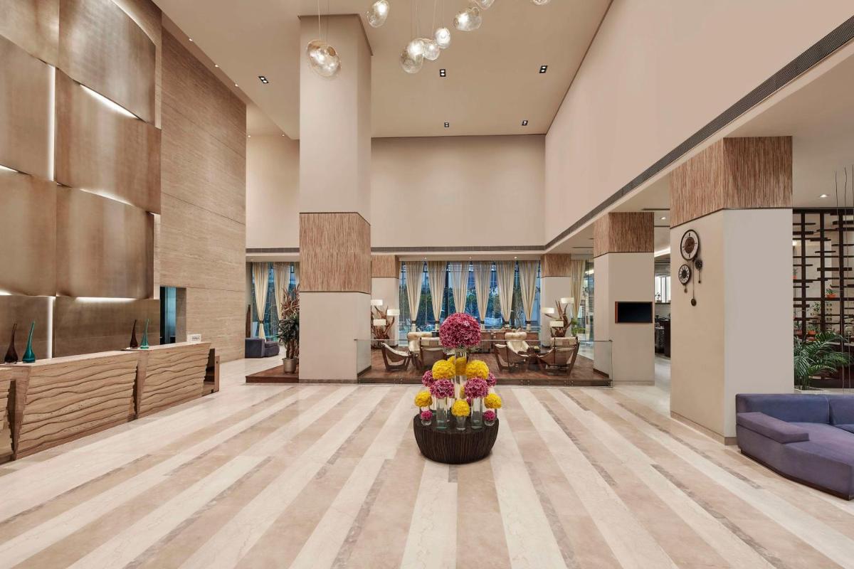 a lobby with a vase of flowers on the floor at DoubleTree by Hilton Gurugram Baani Square in Gurgaon