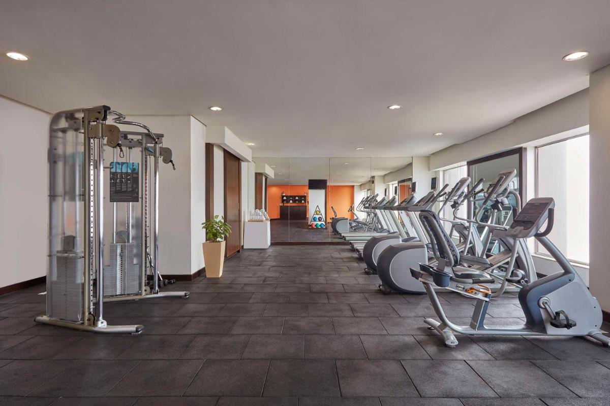 a gym with a row of treadmills and machines at DoubleTree by Hilton Gurugram Baani Square in Gurgaon