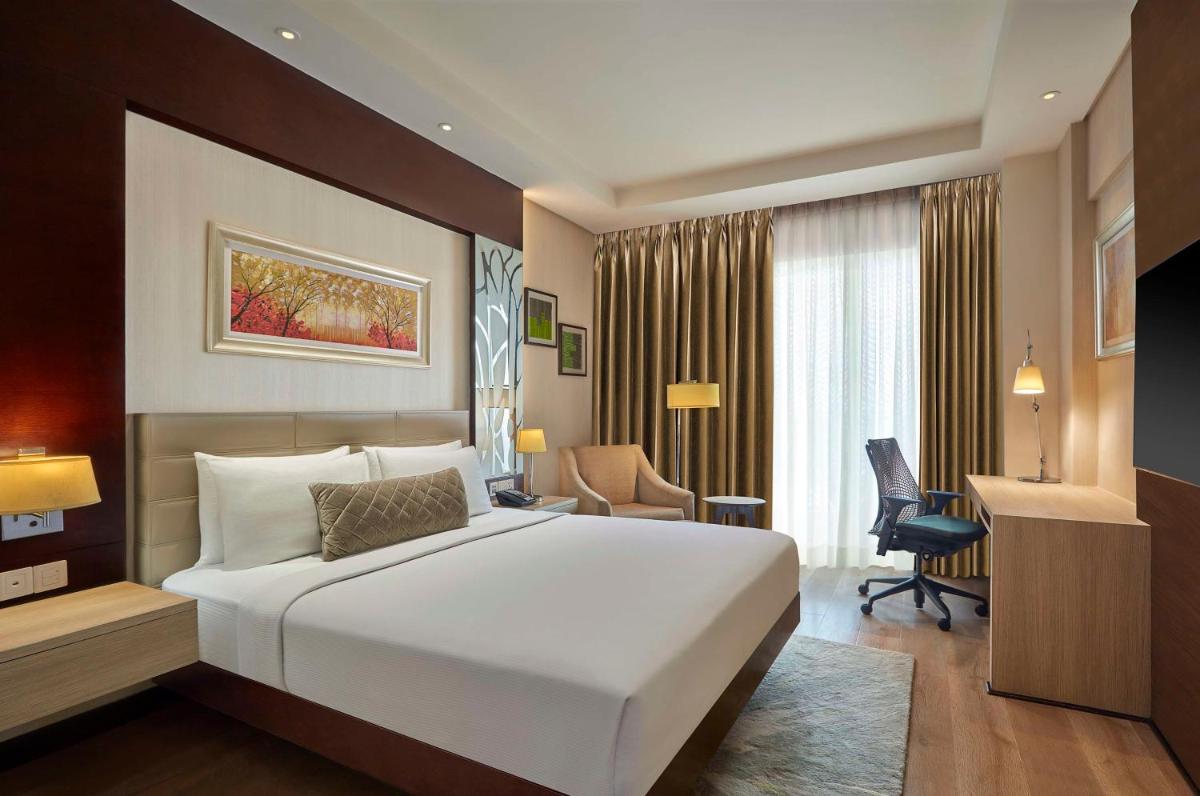 a bedroom with a large white bed and a desk at DoubleTree by Hilton Gurugram Baani Square in Gurgaon a bedroom with a large white bed and a desk at DoubleTree by Hilton Gurugram Baani Square in Gurgaon