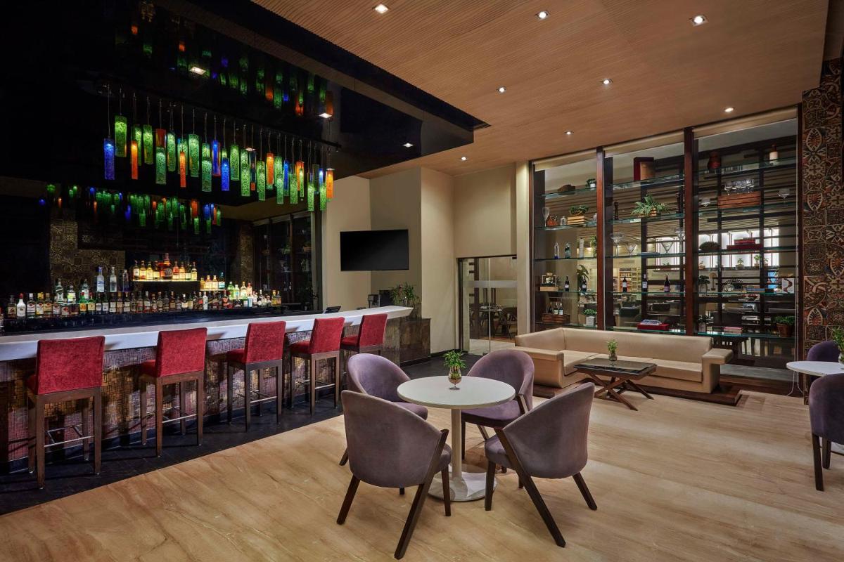 a restaurant with a bar with chairs and tables at DoubleTree by Hilton Gurugram Baani Square in Gurgaon