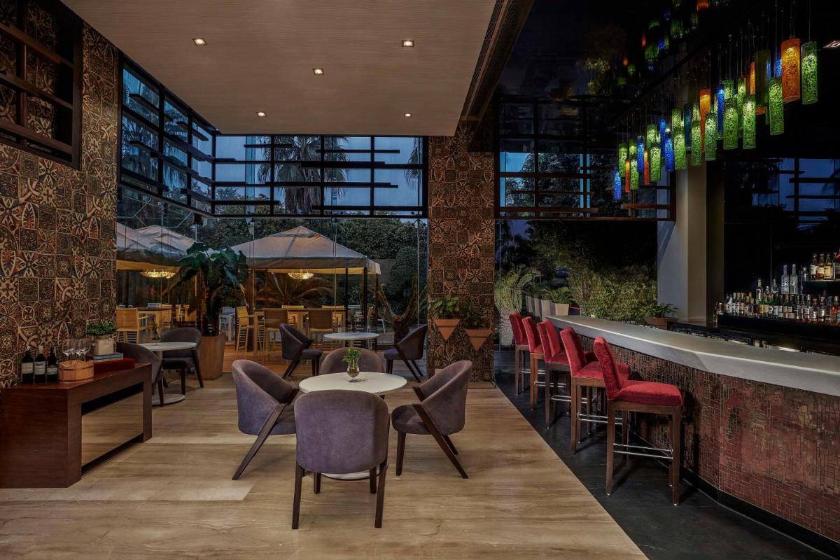 a restaurant with chairs and tables and a bar at DoubleTree by Hilton Gurugram Baani Square in Gurgaon