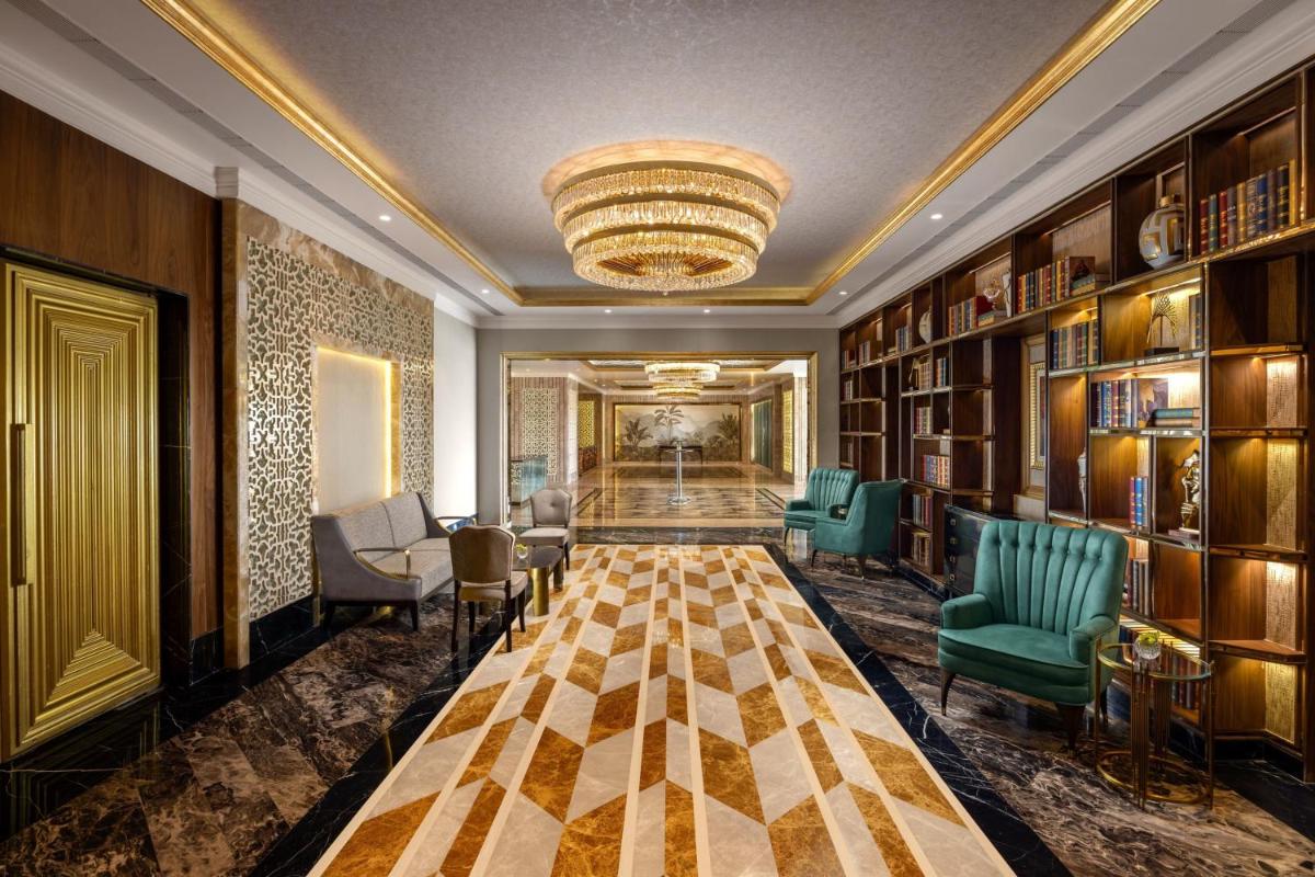 a lobby with a library with green chairs and a chandelier at The St. Regis Mumbai in Mumbai