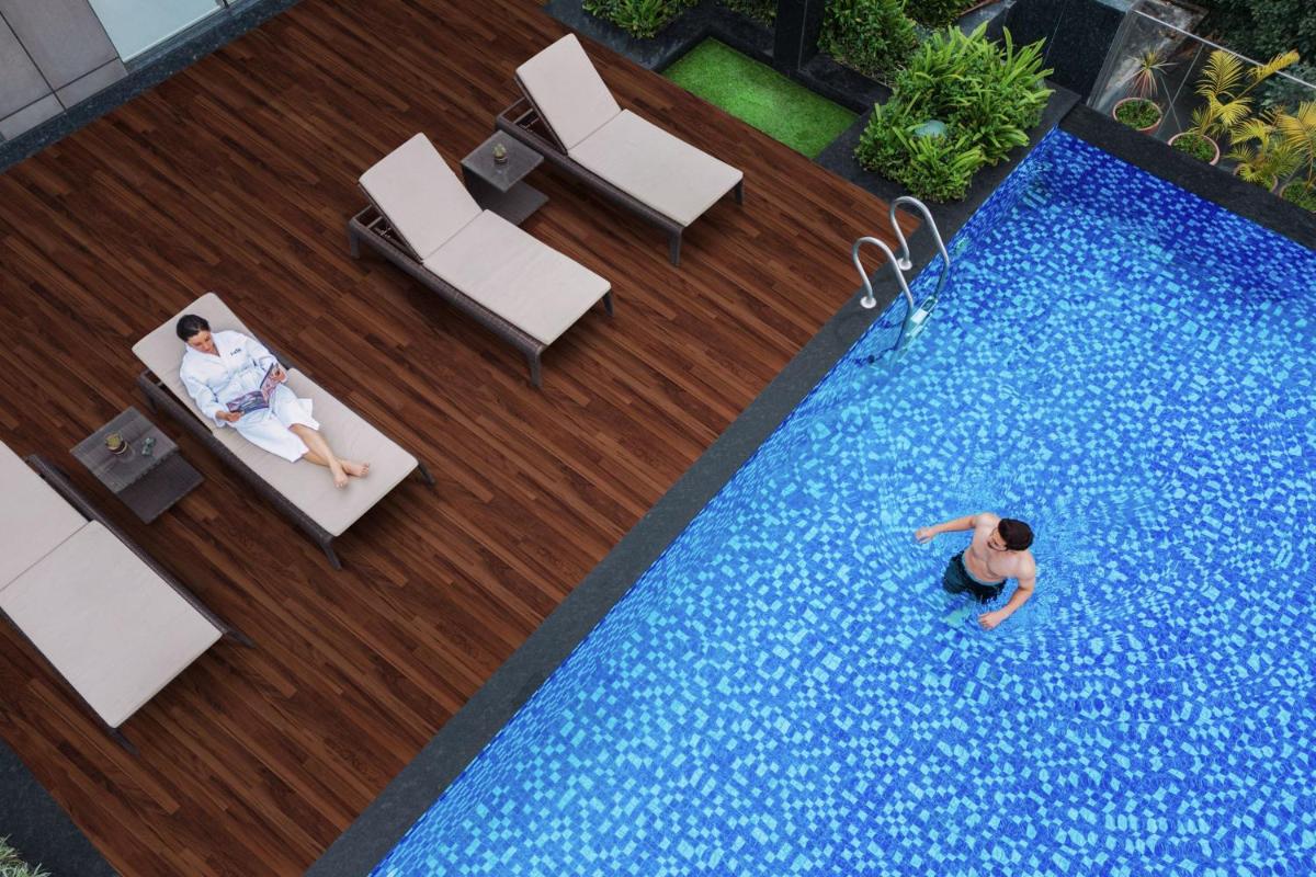 a man in a swimming pool with two people sitting on chairs at Fairfield by Marriott Dehradun in Dehradun