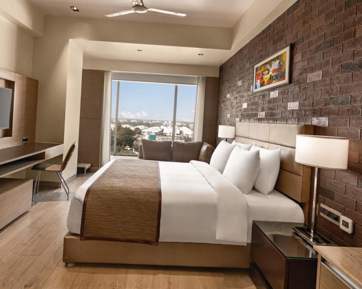 a hotel room with a bed and a large window at Wyndham Ahmedabad Shela in Ahmedabad