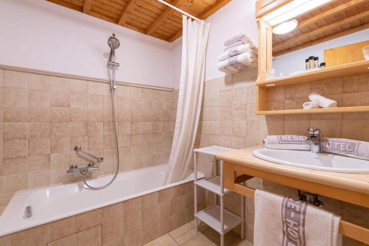 La salle de bains est pourvue d'une baignoire, d'une douche et d'un lavabo. dans l'établissement Hôtel Les Côtes, Résidence Loisirs et Chalets, à Morzine