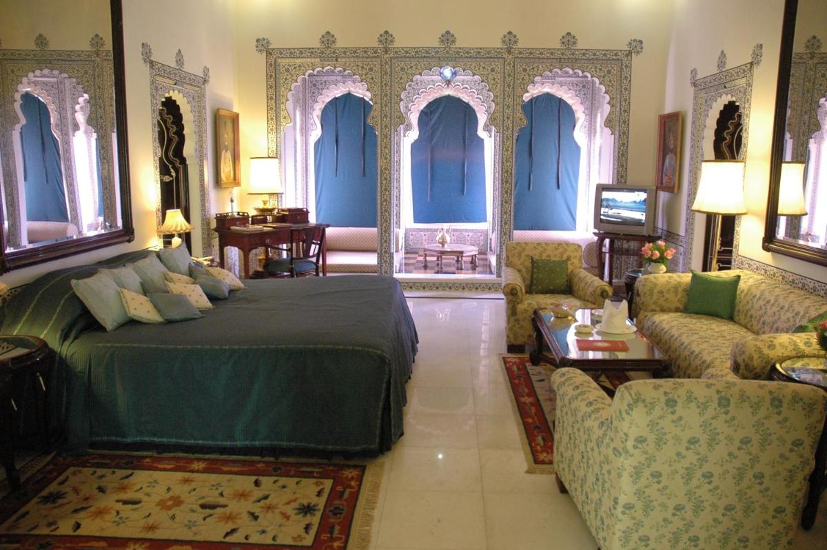 a bedroom with blue walls and a bed and a couch at Shiv Niwas Palace by HRH Group of Hotels in Udaipur
