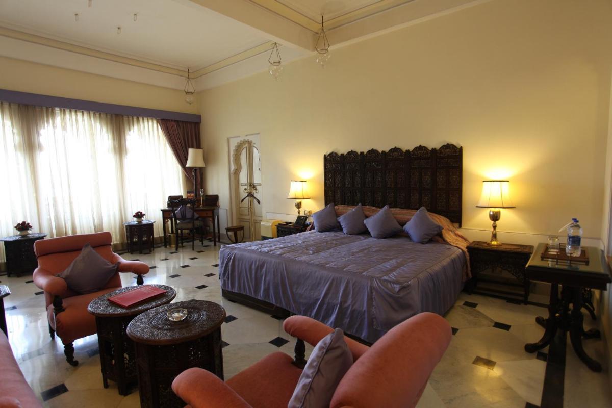 a bedroom with a large bed and chairs in it at Shiv Niwas Palace by HRH Group of Hotels in Udaipur