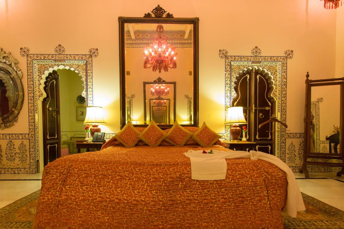 a bedroom with a large bed and a chandelier at Shiv Niwas Palace by HRH Group of Hotels in Udaipur