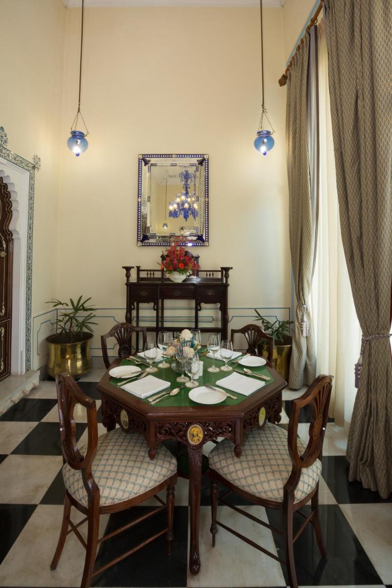 a dining room with a table with chairs and a mirror at Shiv Niwas Palace by HRH Group of Hotels in Udaipur