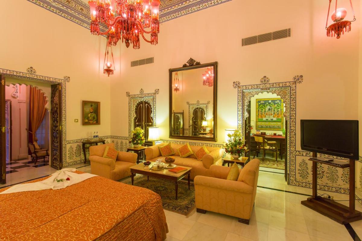 a living room with a bed and a tv in it at Shiv Niwas Palace by HRH Group of Hotels in Udaipur