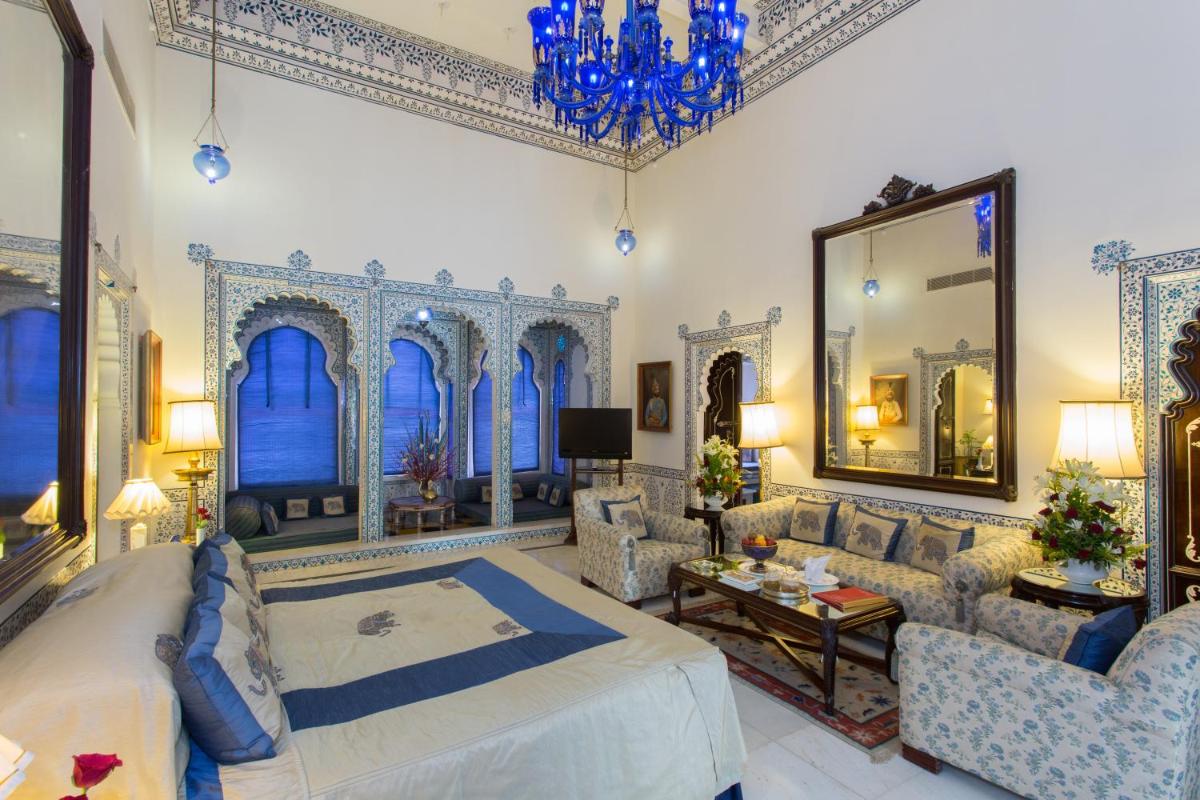a bedroom with a bed and chairs and a mirror at Shiv Niwas Palace by HRH Group of Hotels in Udaipur