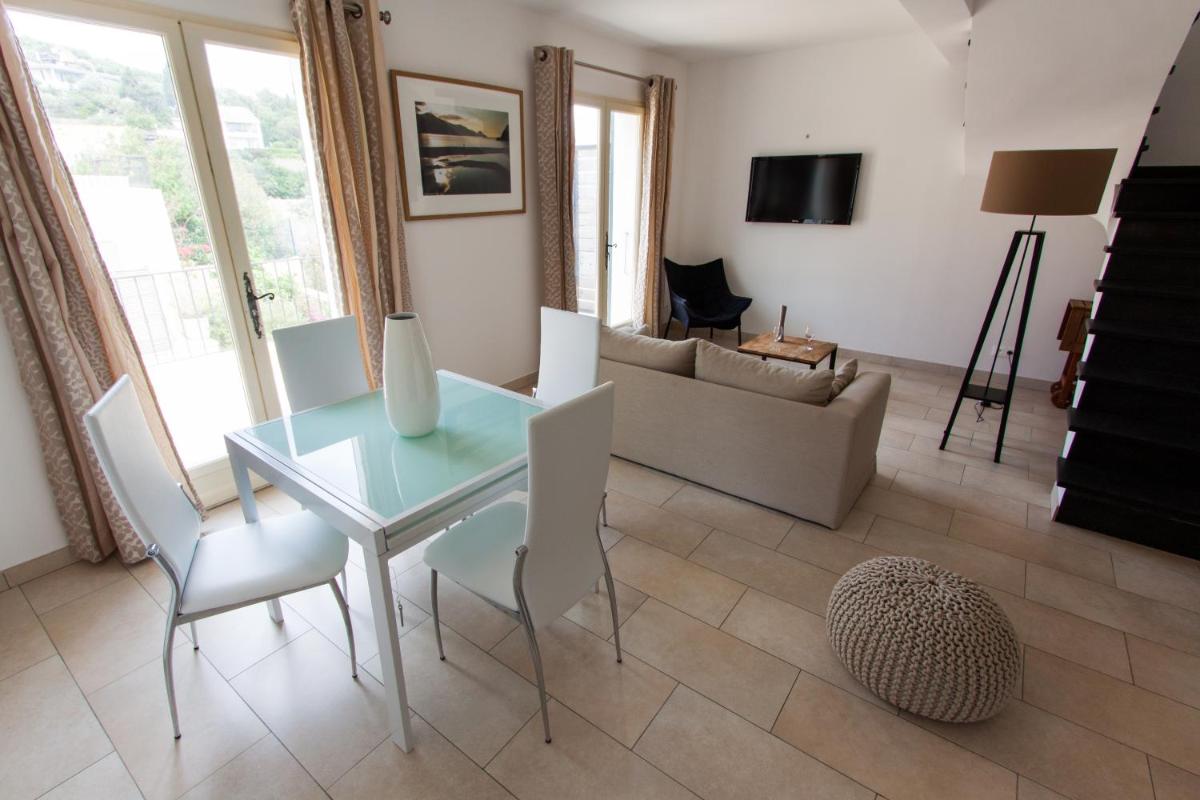 - un salon avec une table en verre et des chaises blanches dans l'établissement Erbalunga - Résidence Les Bosquets - Cap corse Location, à Brando