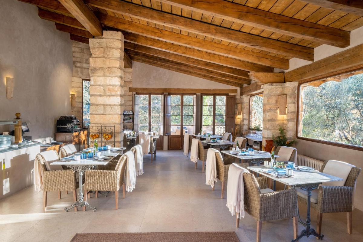 Un comedor con mesas y sillas y ventanas. en Finca Ratxo Hotel, member of Melia Collection, en Puigpunyent