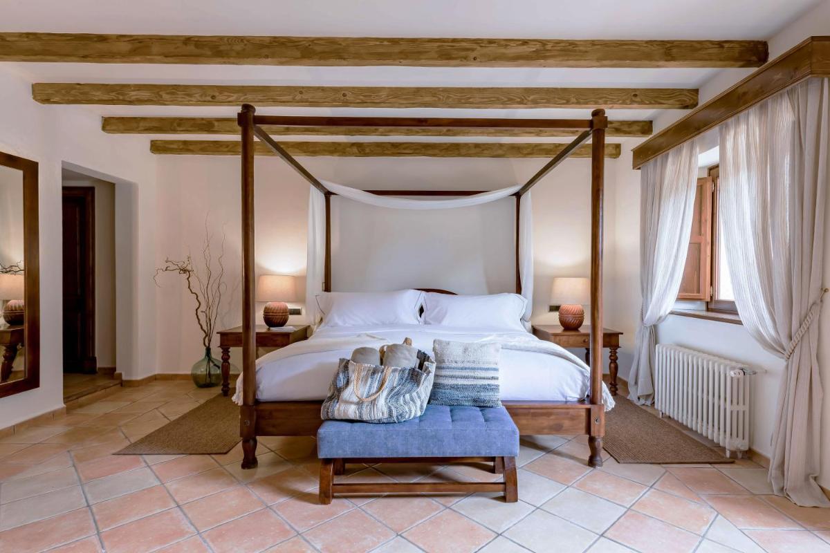 1 dormitorio con cama con dosel y silla azul en Finca Ratxo Hotel, member of Melia Collection, en Puigpunyent