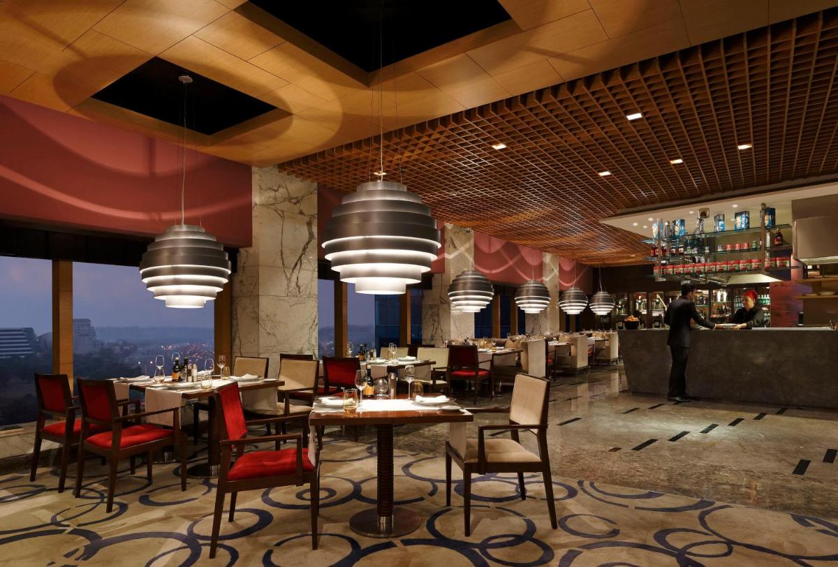 a restaurant with tables and chairs and a bar at The Leela Ambience Gurugram Hotel & Residences - The Luxury Urban Sanctuary in Gurgaon