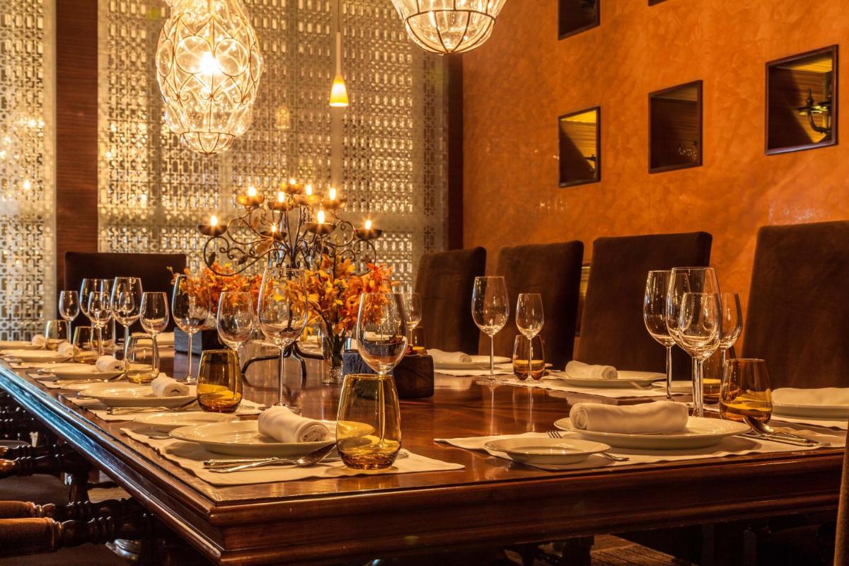 a long table with glasses and plates on it at The Leela Ambience Gurugram Hotel & Residences - The Luxury Urban Sanctuary in Gurgaon