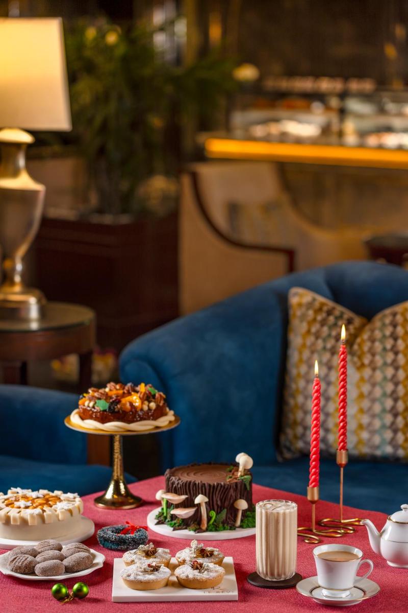 a table topped with different types of cakes and candles at The Leela Ambience Gurugram Hotel & Residences - The Luxury Urban Sanctuary in Gurgaon
