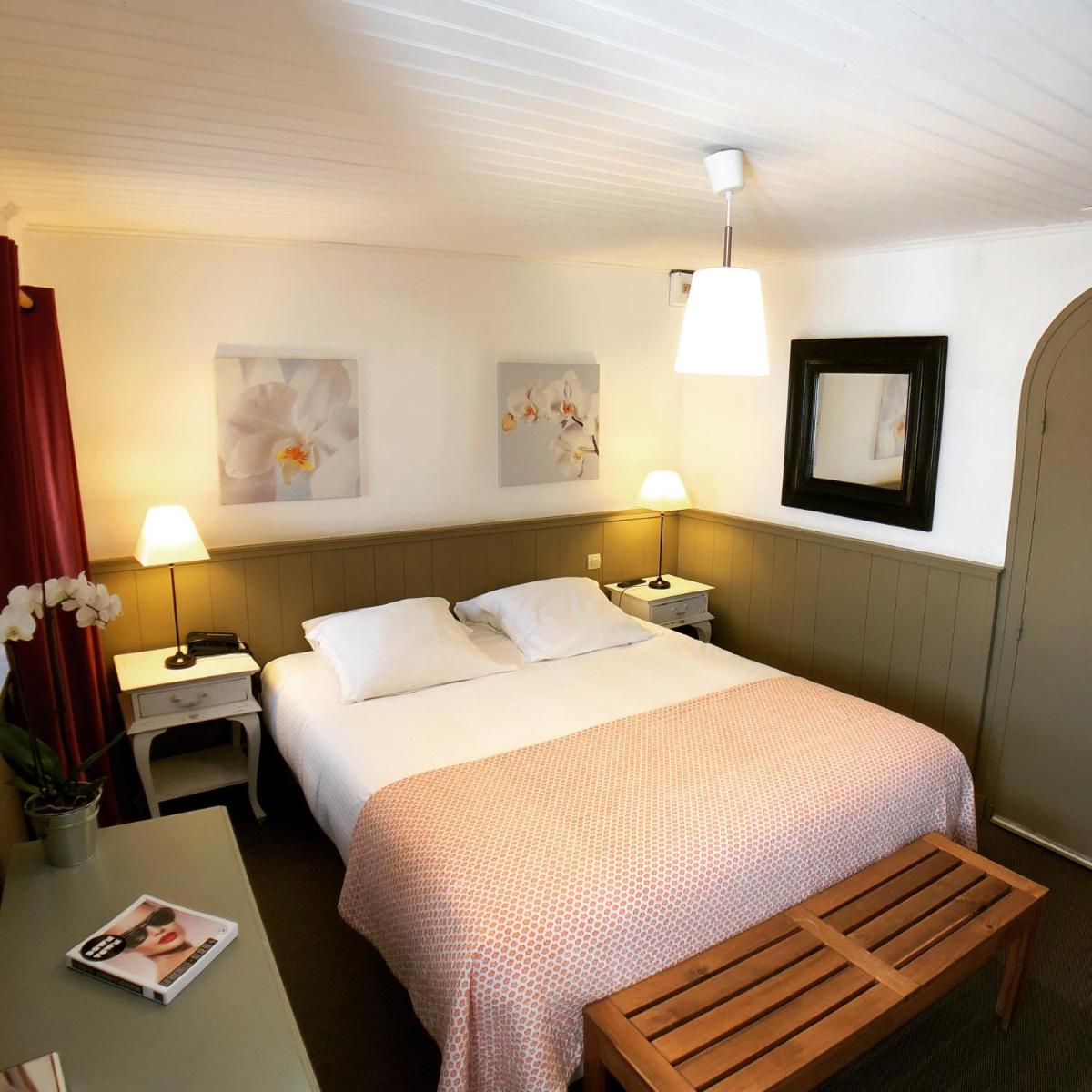 une chambre avec un lit, une table et deux lampes dans l'établissement Hotel L'Océan, au Bois-Plage-en-Ré