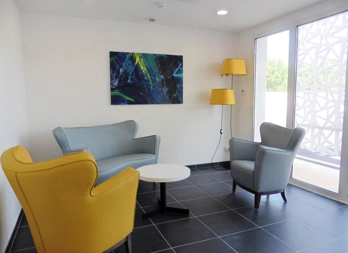 une salle d'attente avec des chaises, une table et un tableau dans l'établissement Appart'Hotel Odalys Nakâra, au Cap d'Agde