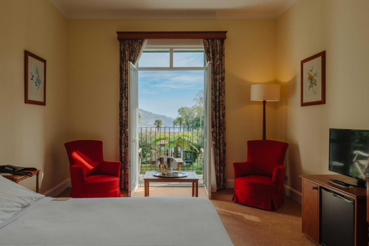 um quarto de hotel com uma cama e duas cadeiras e uma janela em Quinta da Bela Vista no Funchal