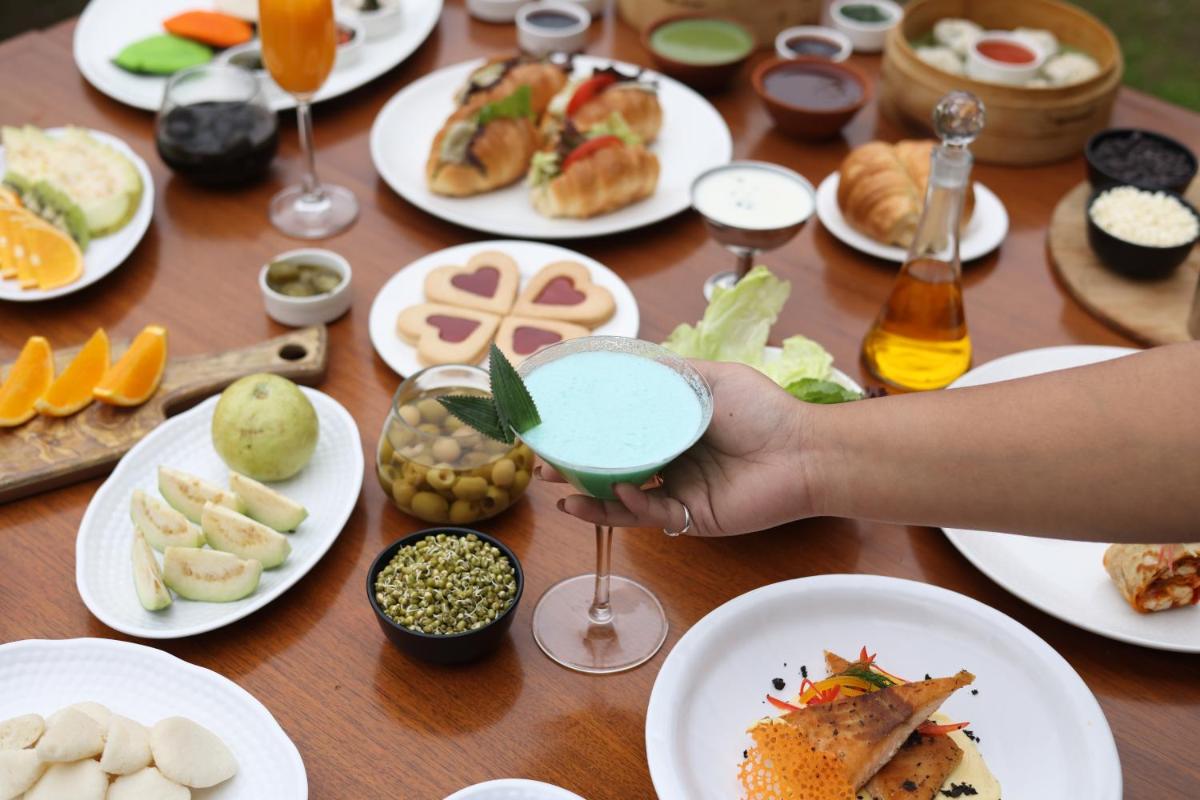 a person holding a drink in front of a table of food at Holiday Inn Agra MG Road an IHG Hotel in Agra