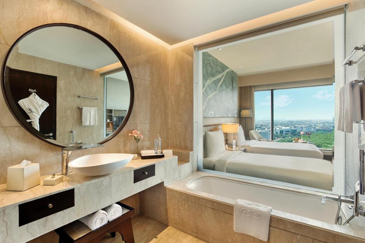 a bathroom with a tub and a sink and a mirror at The Leela Ambience Convention Hotel Delhi in New Delhi