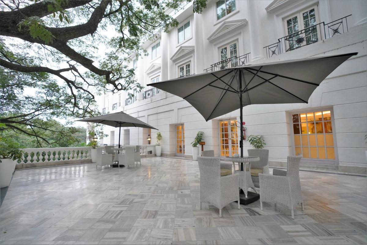 a patio with tables and umbrellas in front of a building at ITC Windsor, a Luxury Collection Hotel, Bengaluru in Bengaluru a patio with tables and umbrellas in front of a building at ITC Windsor, a Luxury Collection Hotel, Bengaluru in Bengaluru