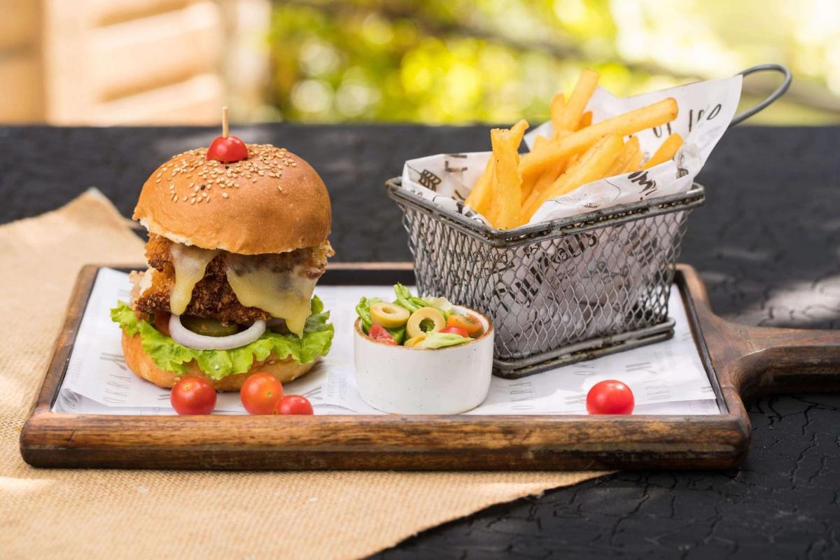 a plate with a sandwich and a basket of fries at Hyderabad Marriott Hotel & Convention Centre in Hyderabad