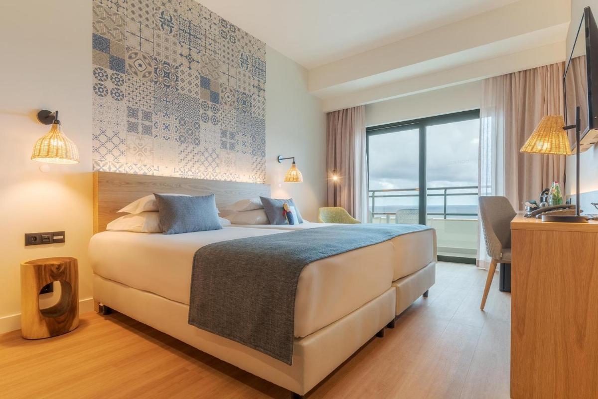 um quarto de hotel com uma cama grande e uma janela em Sentido Galosol no Caniço