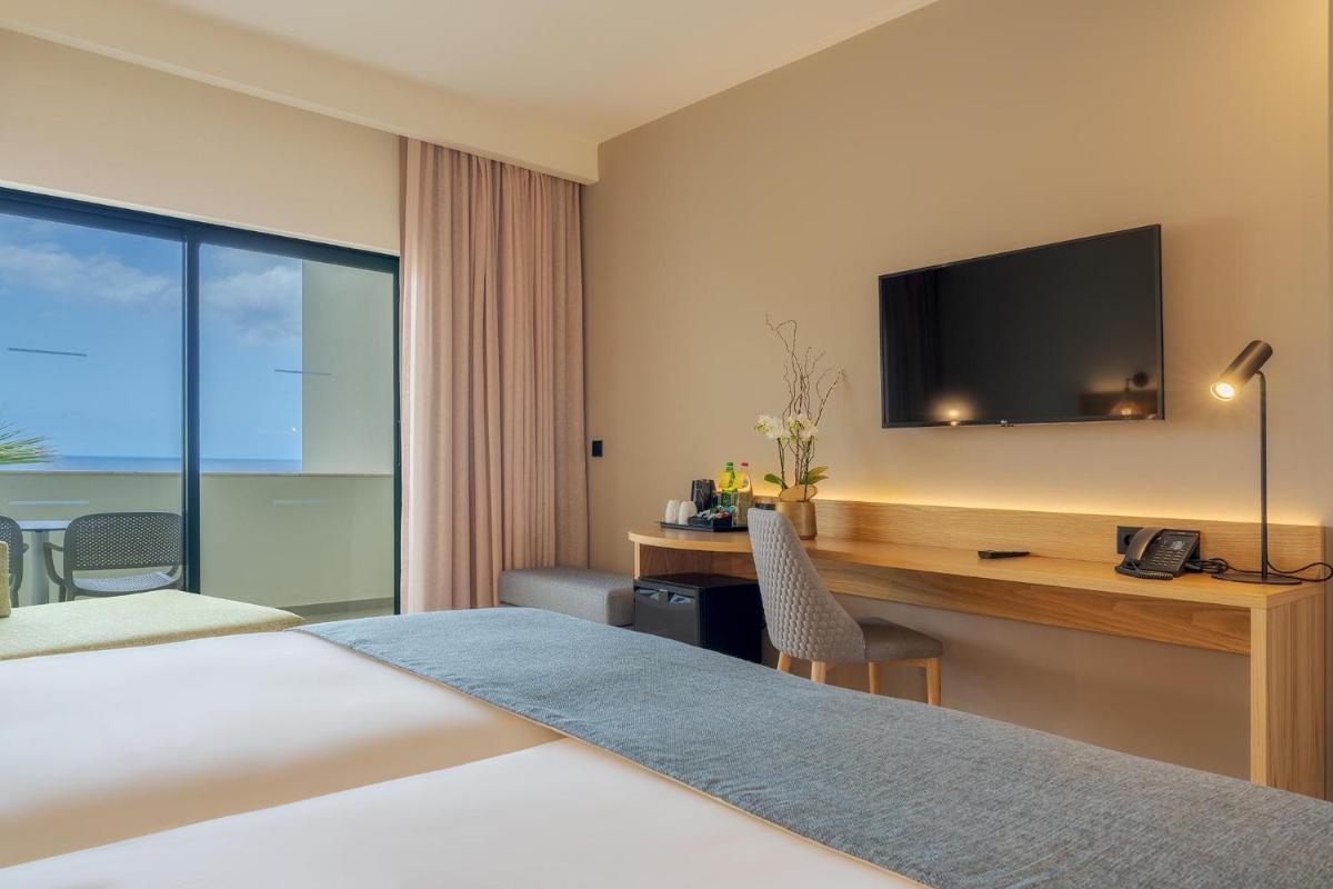 um quarto de hotel com uma cama e uma escrivaninha com uma televisão em Sentido Galosol no Caniço