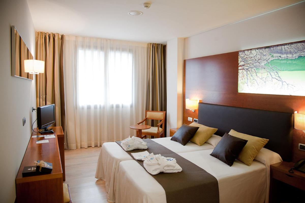una habitación de hotel con una cama y un televisor en Hotel Balneario Valle del Jerte, en Valdastillas