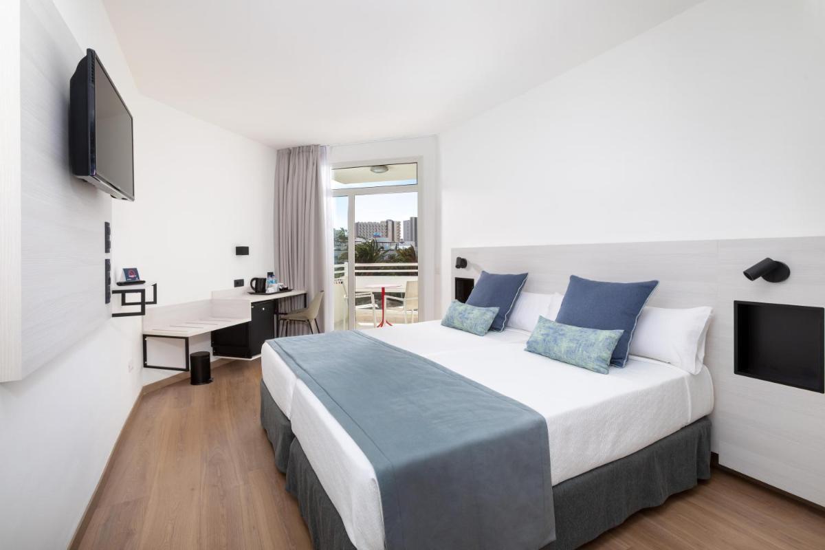 Un dormitorio con una cama, un escritorio y un televisor. en Alexandre Troya, en Playa de las Américas
