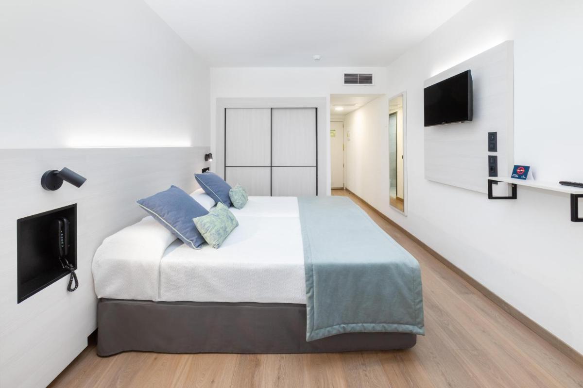 Un dormitorio blanco con una cama grande con almohadas azules. en Alexandre Troya, en Playa de las Américas