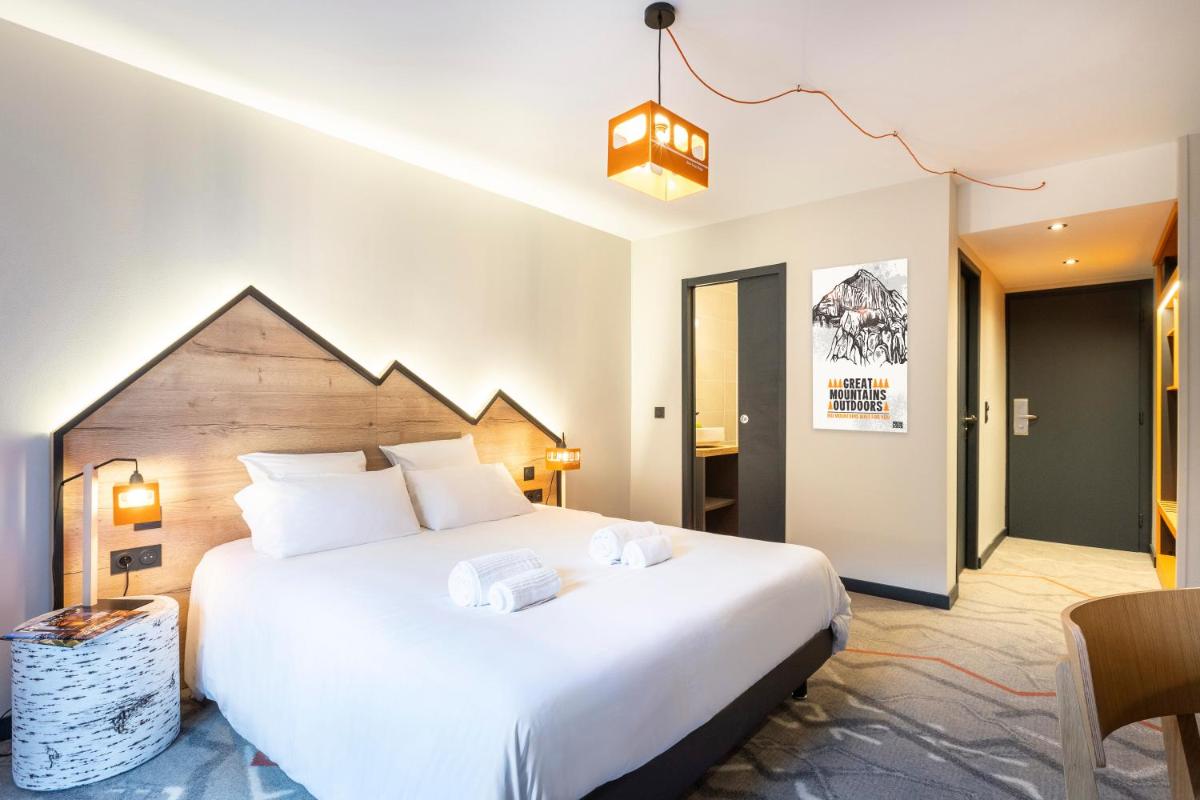 une chambre avec un grand lit blanc dans une pièce dans l'établissement Hotel Base Camp Lodge - Albertville, à Albertville