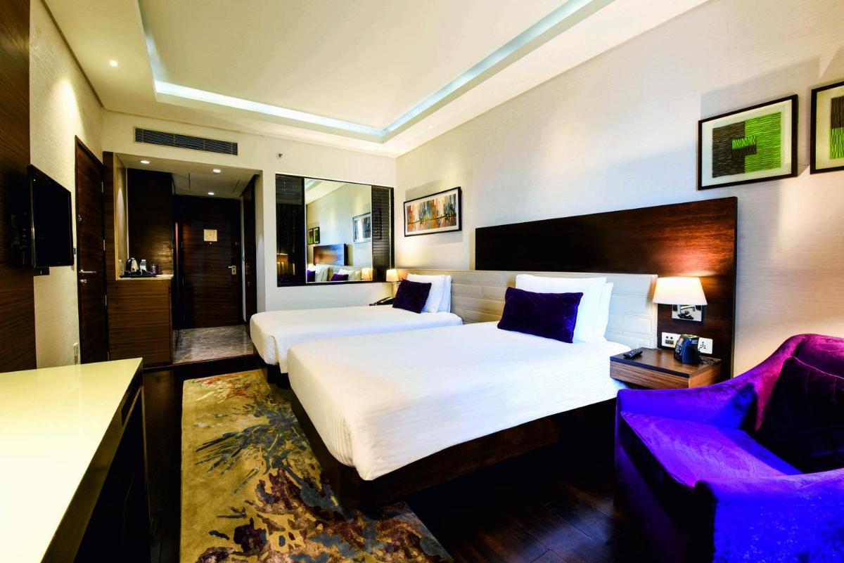 a hotel room with two beds and a couch at DoubleTree by Hilton Gurugram Baani Square in Gurgaon