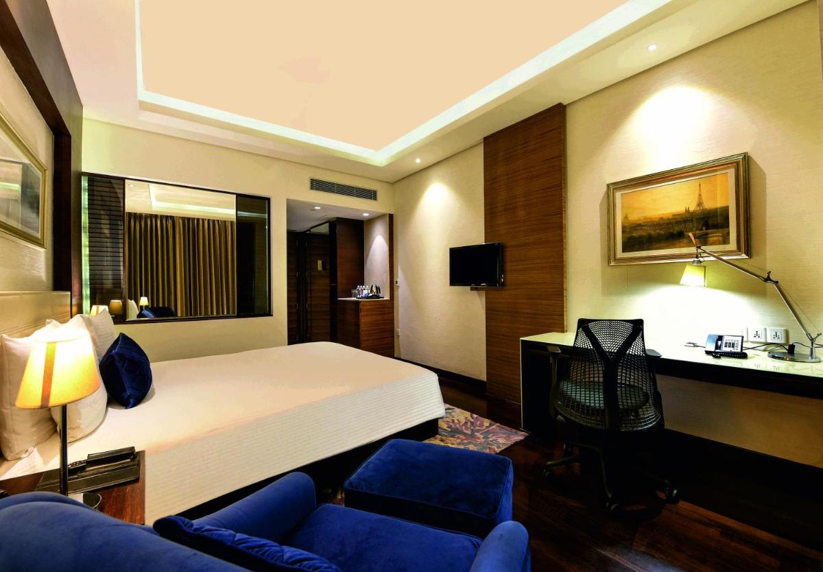 a hotel room with a bed and a blue couch at DoubleTree by Hilton Gurugram Baani Square in Gurgaon