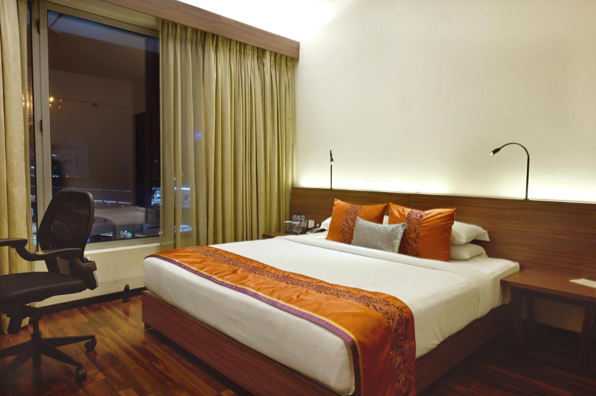 a hotel room with a bed and a desk and a chair at Vivanta Kolkata EM Bypass in Kolkata