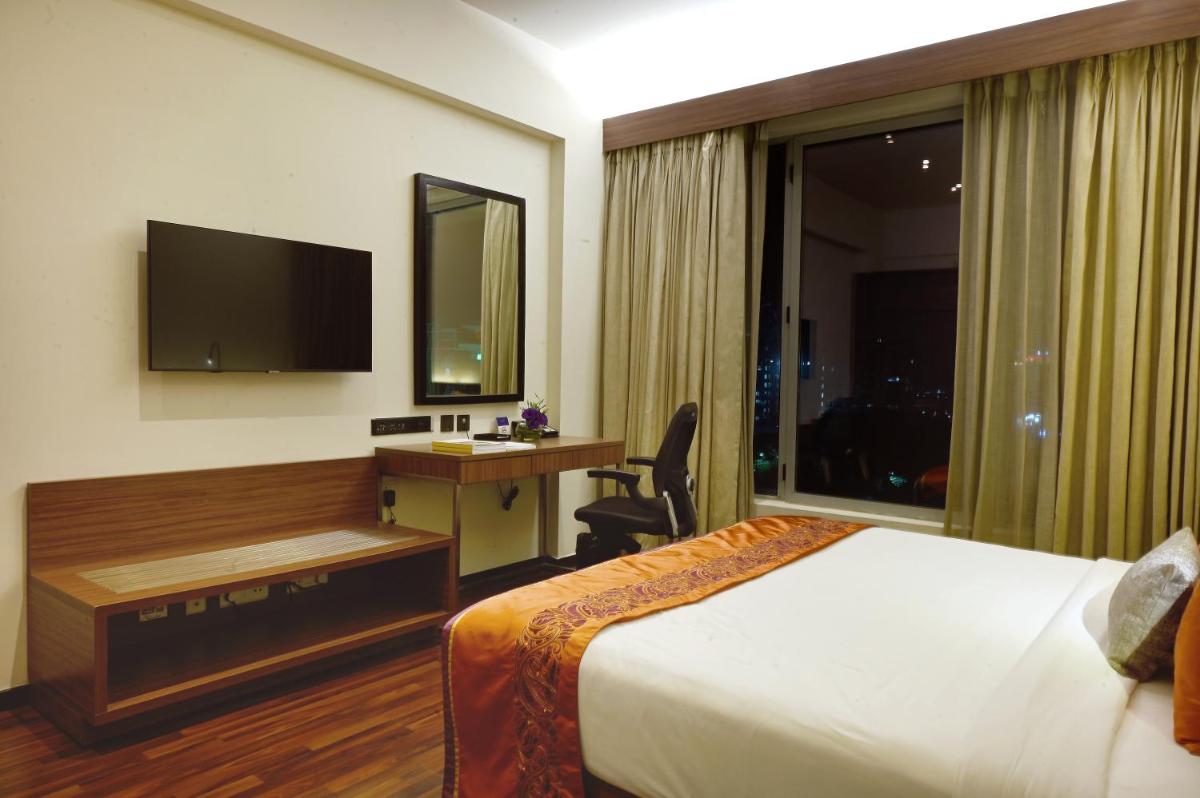 a hotel room with a bed and a desk and a television at Vivanta Kolkata EM Bypass in Kolkata