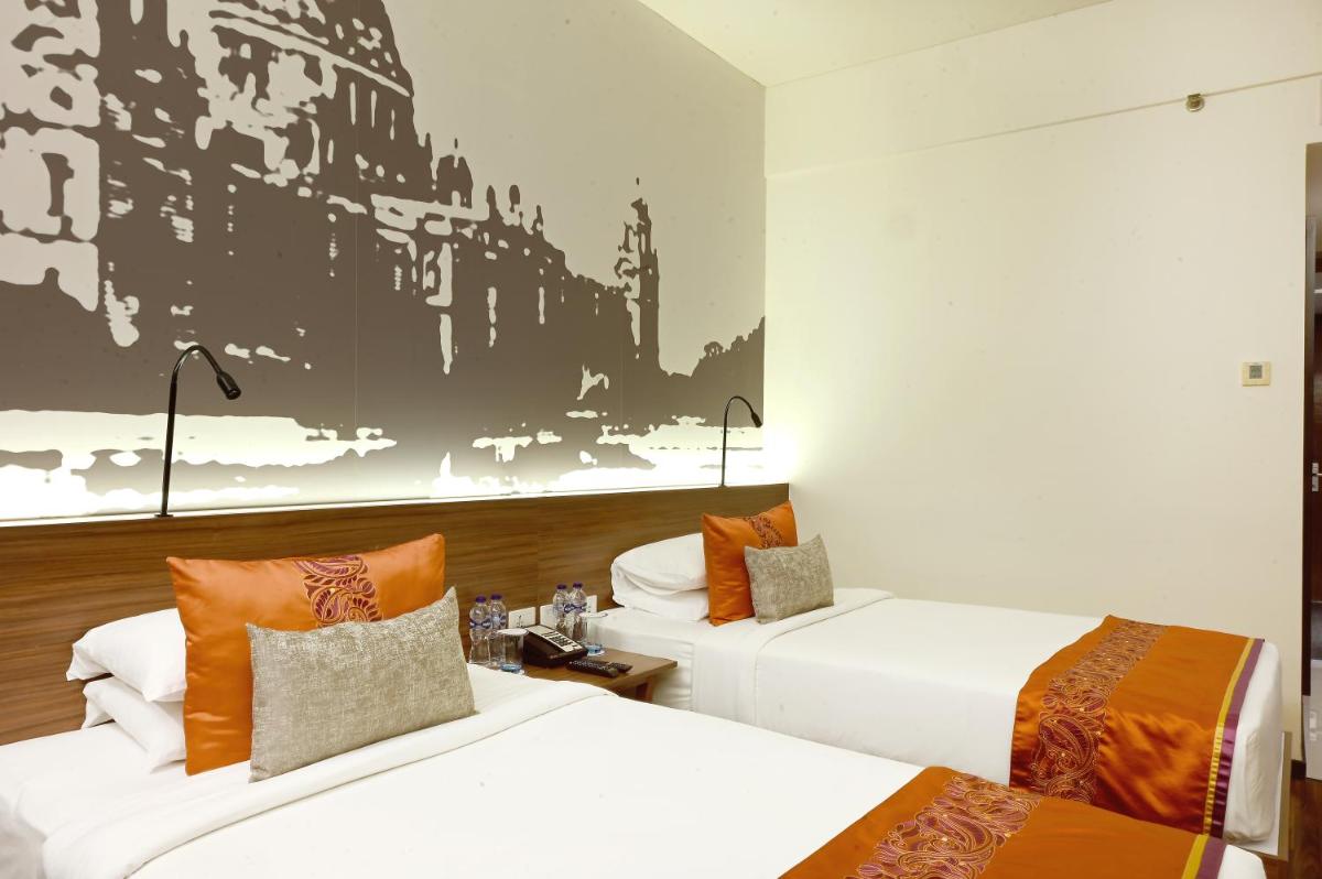 a hotel room with two beds and a painting on the wall at Vivanta Kolkata EM Bypass in Kolkata